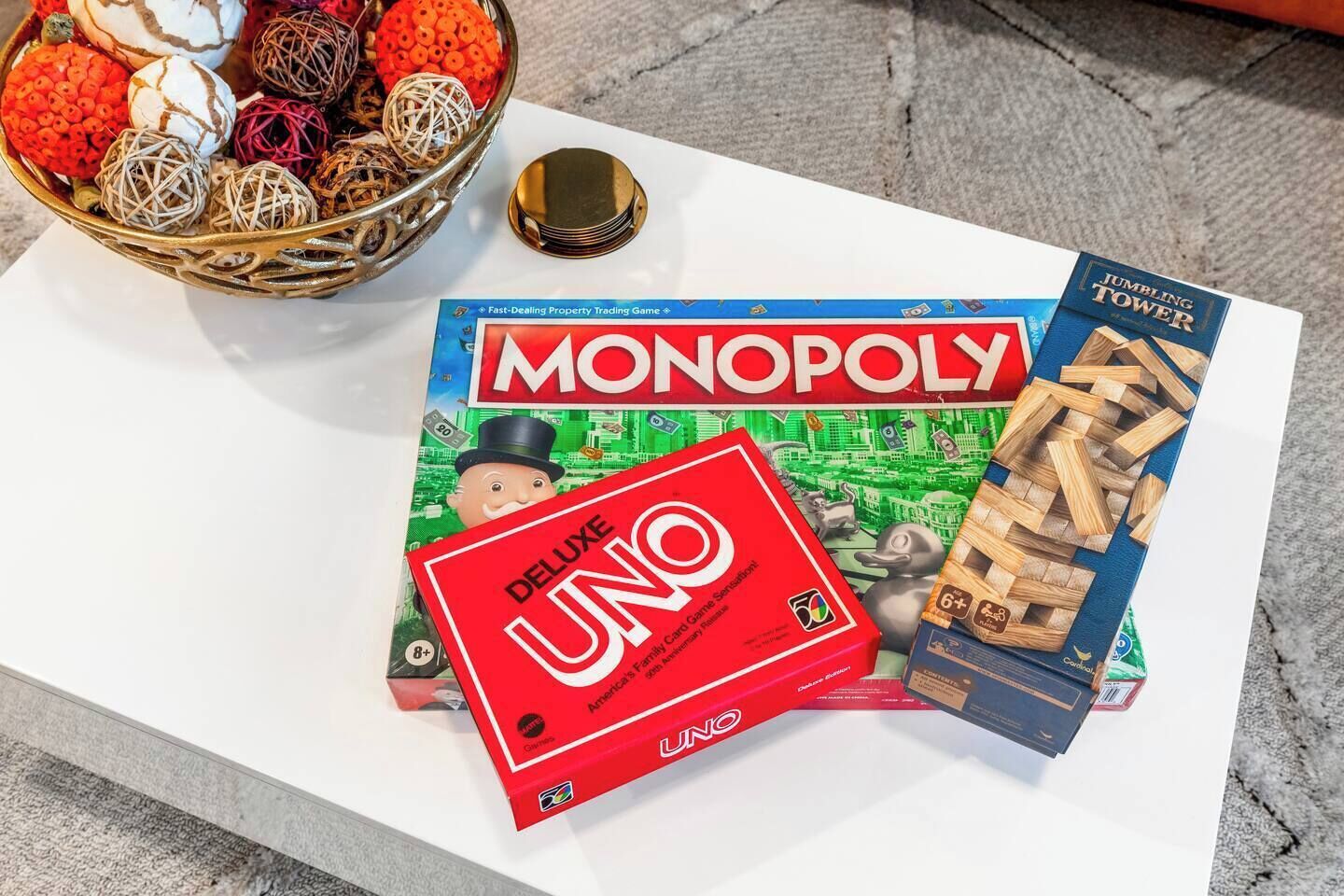 A Monopoly board game, UNO, and JUMBLING TOWER on a white table.