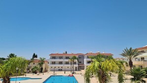 A hotel with a swimming pool, palm trees, and a clear blue sky. - Narcissos 'Nissi Beach' apartment C16 (Ayia Napa)