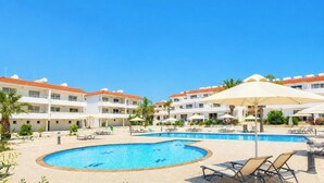 A hotel with a swimming pool, sun loungers, and umbrellas. - Narcissos 'Nissi Beach' apartment C16 (Ayia Napa)