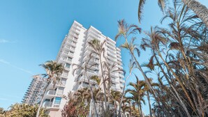 A tall, multi-story hotel with balconies, surrounded by palm trees. - Lovers Key: Amazing Views with private beach/pool! (Fort Myers Beach)