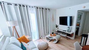 A modern living room with a sofa, ottoman, and a flat-screen TV. - Lovers Key: Amazing Views with private beach/pool! (Fort Myers Beach)