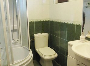 Une salle de bain comprenant des toilettes, un lavabo et un espace douche.