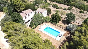 Vue aérienne d’une propriété comprenant une piscine, deux bâtiments et la végétation environnante.
