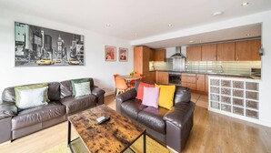 A modern living room with leather sofas, a wooden coffee table, and a cityscape painting. - Quayside Apartment - Central Location (Dundee)