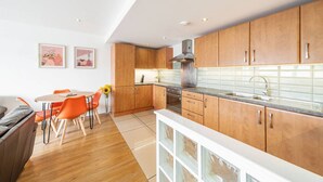 A modern kitchen with wooden cabinets, a stainless steel range hood, and a white countertop. - Quayside Apartment - Central Location (Dundee)