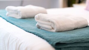 A neatly made bed with white and teal bedding. - The Palais - Retro Style (Dundee)