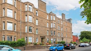 A multi-story residential building with a brick facade, multiple windows, and a front garden with a bench. - The Palais - Retro Style (Dundee)