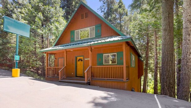 A lodge with a front porch, a green door, and a signboard. - Aspen- Spacious River Front, family cabin (Strawberry)