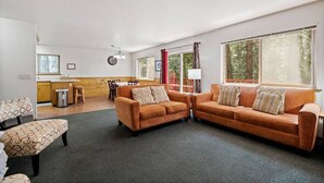 A spacious living room with a large window, a dining area, and a kitchen. - Aspen- Spacious River Front, family cabin (Strawberry)