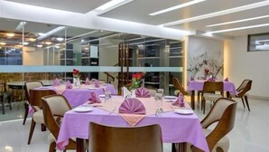 A dining area with tables set for four, each with a purple tablecloth and matching napkins. - Grand Mostafa Hotel Ababil (Sylhet)