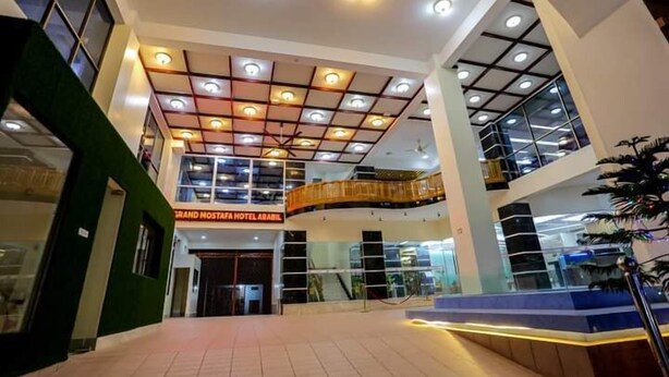 A hotel lobby with a modern design, featuring a central atrium, multiple levels, and a prominent staircase. - Grand Mostafa Hotel Ababil (Sylhet)
