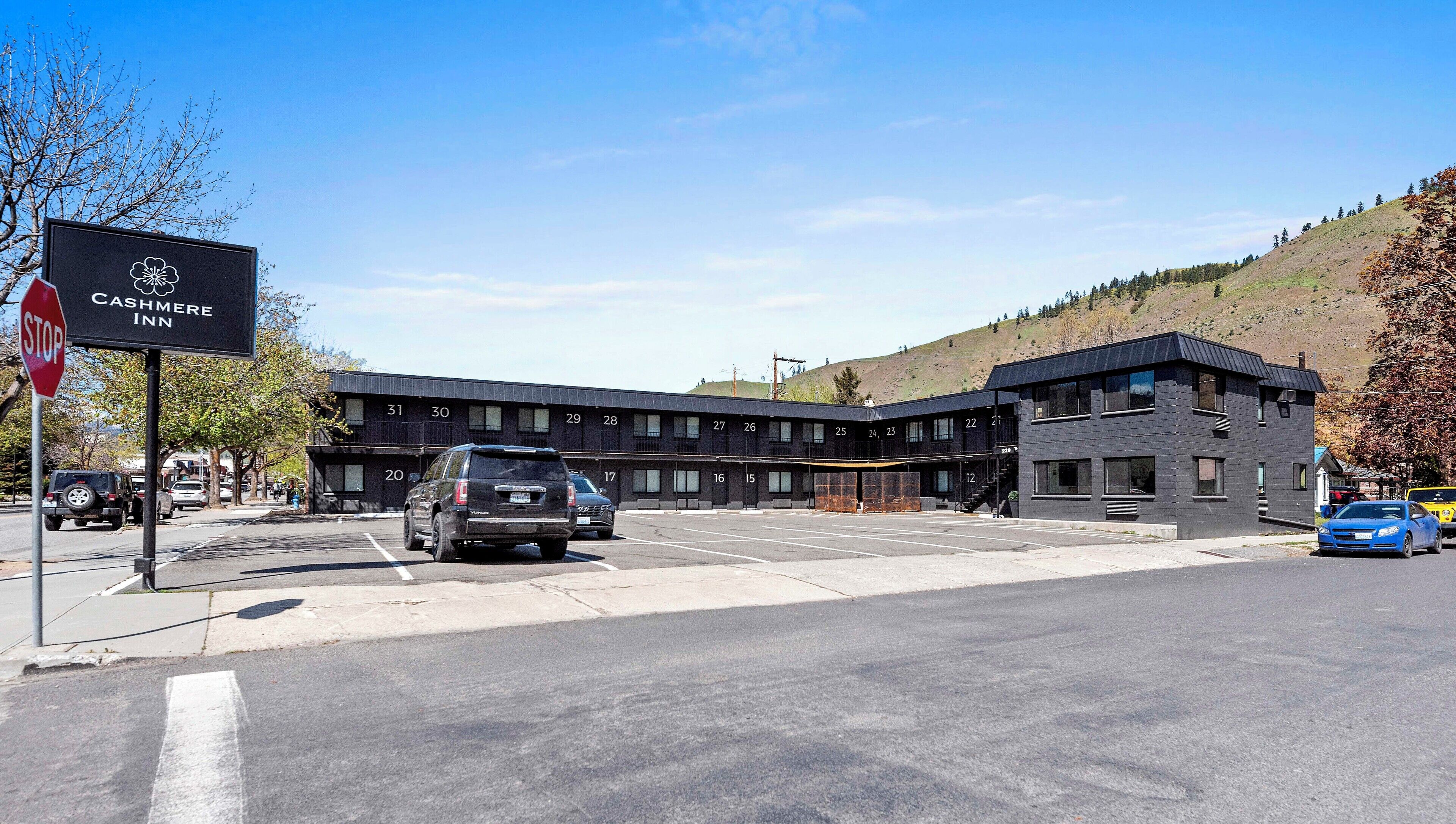 Un edificio moderno con habitaciones numeradas, una señal de stop y un estacionamiento.