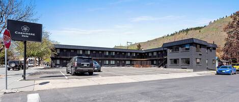 Un edificio moderno con habitaciones numeradas, una señal de stop y un estacionamiento.
