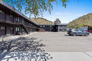 Un edificio moderno con habitaciones numeradas, un estacionamiento y vistas a un paisaje montañoso.