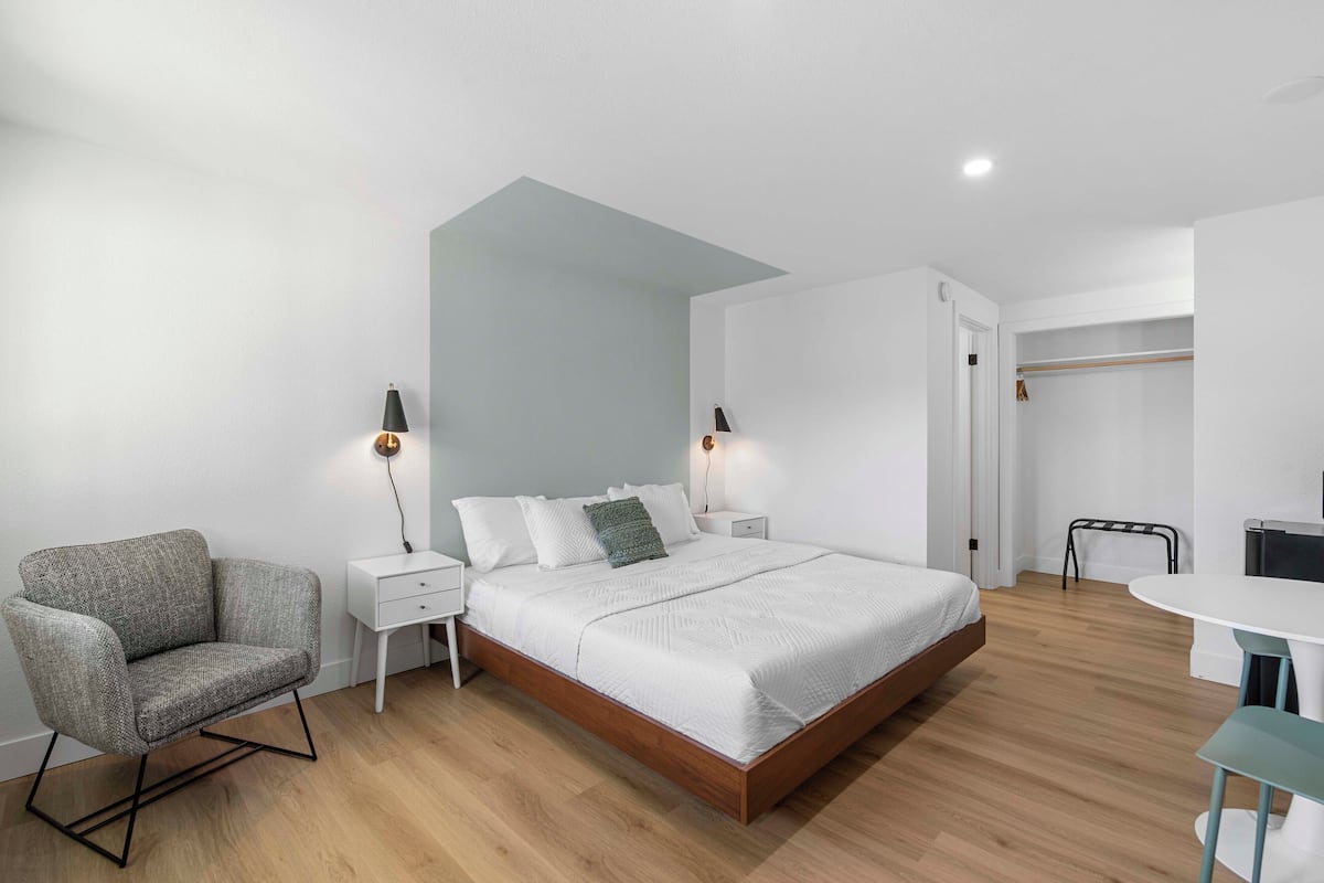 A modern bedroom with a bed, bedside tables, a chair, and a desk.