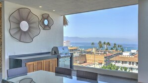 A balcony with a grill, dining area, and decorative wall art. - Beautiful condo in the heart of Zona Romantica and steps to Los Muertos Beach! 1 (Puerto Vallarta)