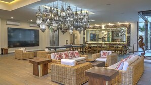A spacious lounge area with wicker furniture, a large chandelier, and a bar with a mirror backsplash. - Beautiful condo in the heart of Zona Romantica and steps to Los Muertos Beach! 1 (Puerto Vallarta)