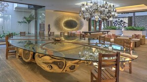 A modern dining area with a glass-top table, wooden chairs, a chandelier, and a decorative wall piece. - Beautiful condo in the heart of Zona Romantica and steps to Los Muertos Beach! 1 (Puerto Vallarta)