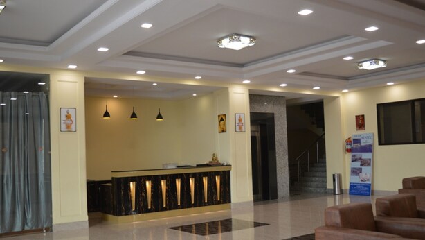 A hotel lobby with a reception desk, seating area, and a staircase leading to the upper floors. - The Sravasti Residency (Ikauna)