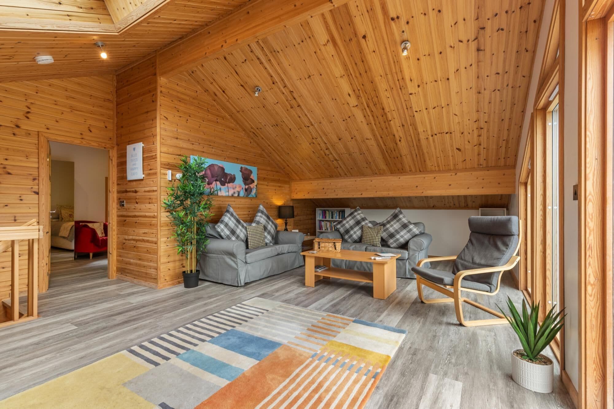 A cozy log cabin interior with a sofa, armchair, and a small table.