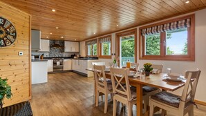 Une cuisine spacieuse dotée de meubles en bois, d’un îlot central et d’un coin repas avec une table dressée pour quatre personnes.