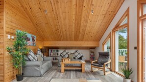 Un salon chaleureux avec un plafond en bois, un canapé gris et une table basse.