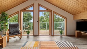 Un vaste espace de vie doté d’un haut plafond, de grandes fenêtres et d’un plancher en bois.