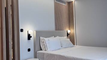 A modern bedroom with a large bed, a round bedside table, and a wall-mounted light fixture.