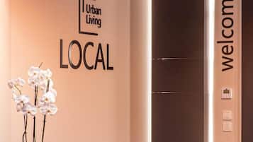 A reception area with a wall sign reading "Urban Living LOCAL" and a "welcome" sign above an elevator.
