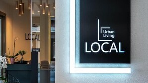 Ein modernes Interieur mit einer Rezeption mit dem Schild "Urban Living LOCAL" und minimalistischer Einrichtung.