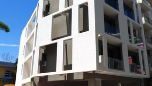 Ein mehrstöckiges Gebäude mit modernem architektonischen Design, das eine Kombination aus rechteckigen und quadratischen Fenstern aufweist.