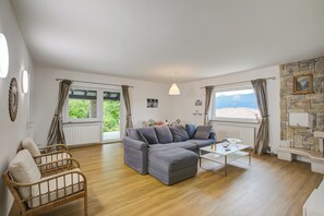 A modern living room with a grey sectional sofa, a wooden coffee table, and a stone fireplace. - Casa Francesca Garden And View (Castelveccana)