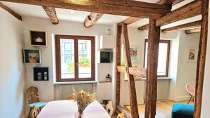 Un espace repas avec une longue table, des poutres en bois et une fenêtre offrant une vue agréable.
