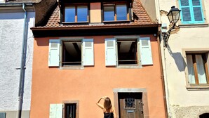 Un bâtiment doté de nombreuses fenêtres, d’une porte et d’un petit balcon.