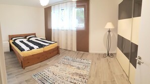 Un dormitorio con cama de madera, alfombra estampada, lámpara de pie y un espejo grande.