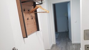 Un pasillo con una puerta de madera, un perchero y una lámpara.