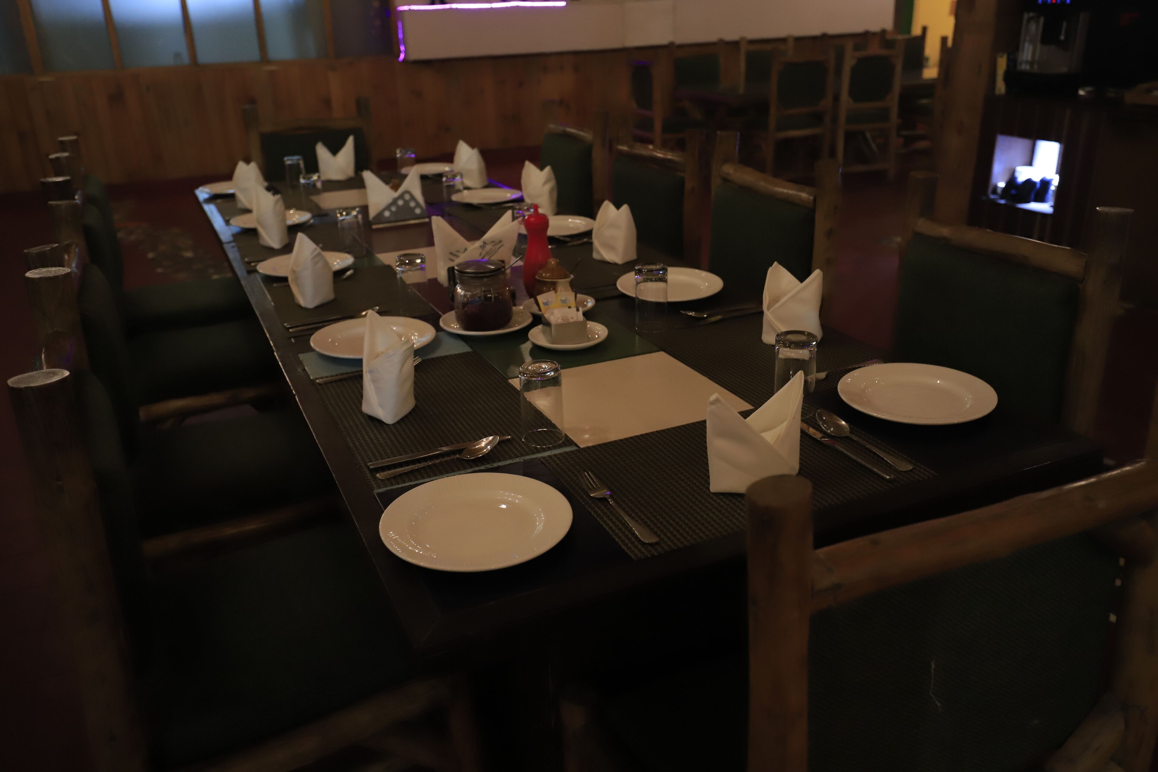 A dining table set with plates, cutlery, and napkins, surrounded by chairs.