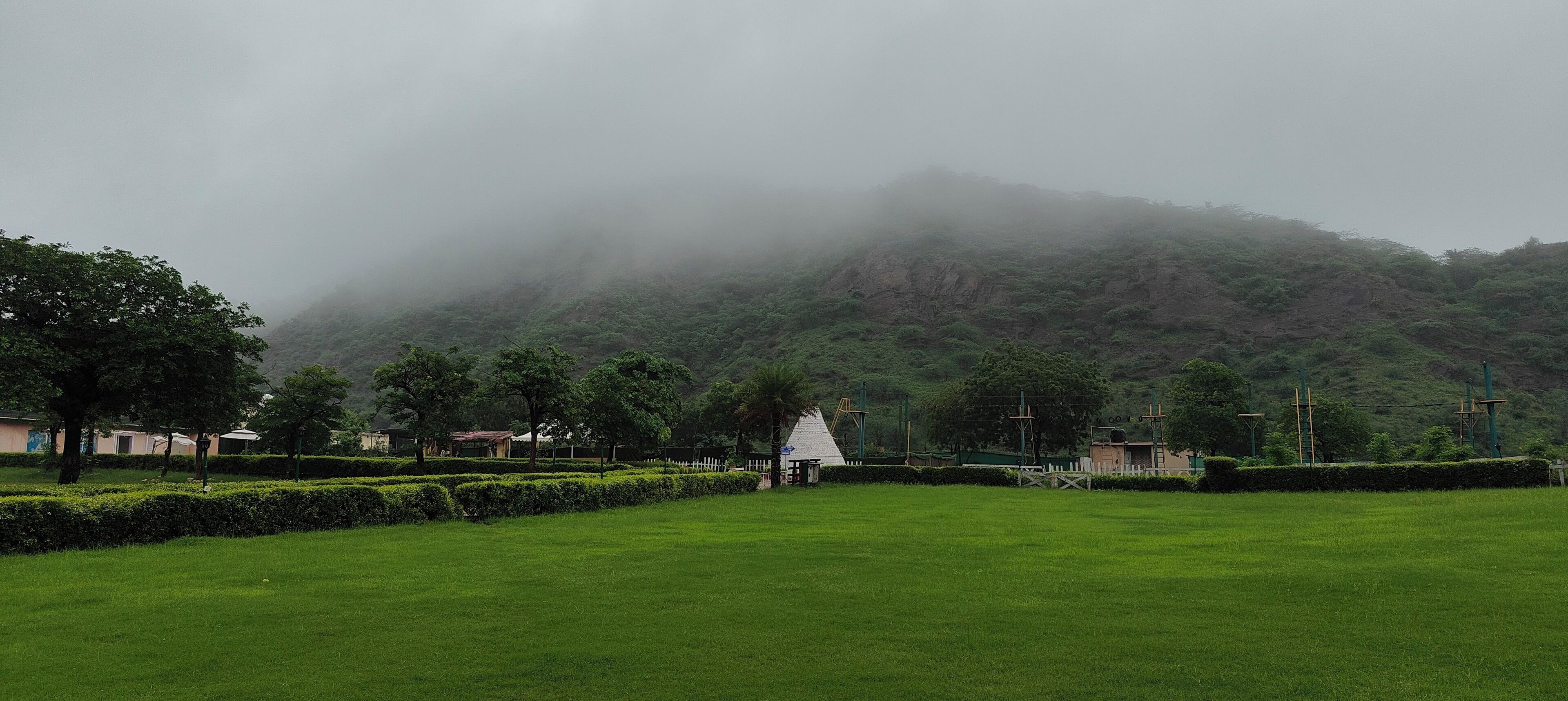 A park with manicured lawns, a white gazebo, and a mountain in the background.