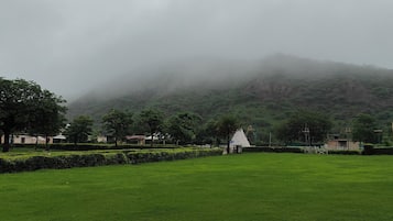 A park with manicured lawns, a white gazebo, and a mountain in the background.