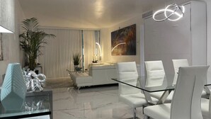 Ein modernes Wohnzimmer mit einem Glastisch, weißen Sofas und einem großen, abstrakten Gemälde.