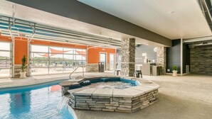 Une piscine avec un jacuzzi, des piliers en pierre et une vue sur l’extérieur.