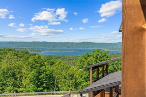 A view from a wooden balcony overlooking a lake surrounded by dense forest.