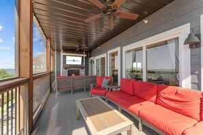 A covered outdoor area with a sofa, chairs, a table, and a fireplace.