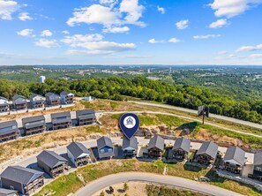 A residential area with multiple houses, a clear sky, and a distant view of a town. - Near Silver Dollar City with Private Hot Tub, Game Area, Community Indoor Pool & Free Daily Tickets (Branson)