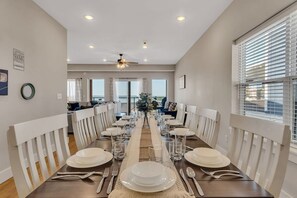 A dining area with a long table set for a meal, white chairs, and a ceiling fan. - Near Silver Dollar City with Private Hot Tub, Game Area, Community Indoor Pool & Free Daily Tickets (Branson)
