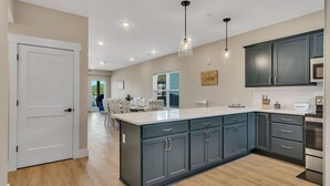 A modern kitchen with dark cabinets, a large island, and pendant lighting.