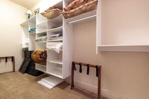 Un dressing accessible sans porte, doté d’étagères ouvertes, d’un porte-chaussures suspendu et d’un escabeau.