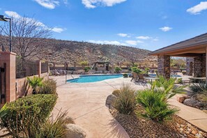 A backyard with a swimming pool, patio furniture, and a stone building. - Ground Floor Suite | Private Balcony, Poolside Access (Hurricane)