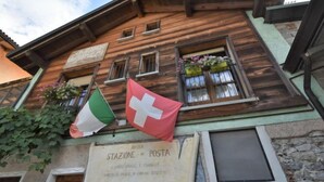 Un bâtiment en bois sur lequel est apposée une enseigne indiquant : « ANTICA STAZIONE DI POSTA CAMMINI CARLIE E CAMPOZZE ».