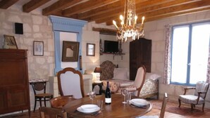 Comedor con mesa y sillas de madera, una araña y una cama con ropa de cama floral.